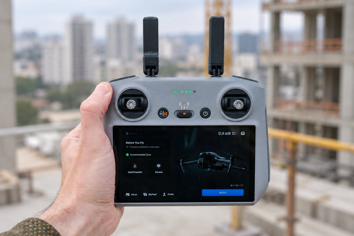 Controle do DJI Air 3S em uso durante a captação, com uma obra ao fundo